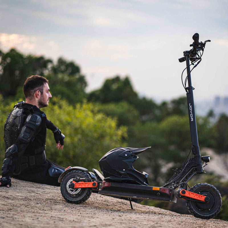Cargue la imagen en el visor de la galería, Person resting with the Joyor S-PRO electric scooter in the mountains, showcasing its durability and comfort for off-road adventures.