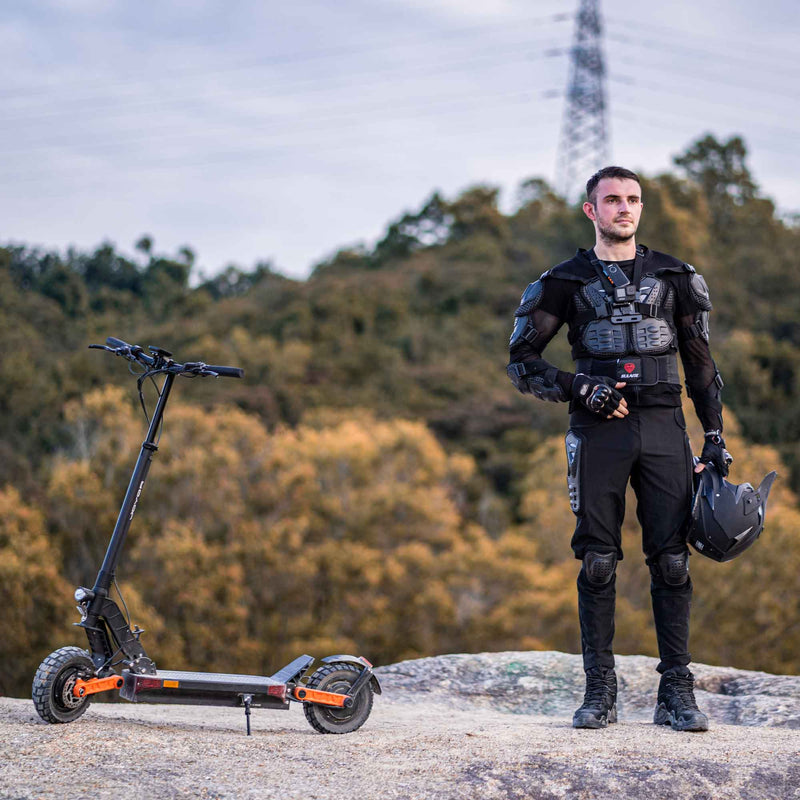 Load image into Gallery viewer, Man stopped with the Joyor S5 ABE / S5-PRO ABE electric scooter on a mountain trail, showcasing its off-road capabilities and rugged design for adventurous rides.
