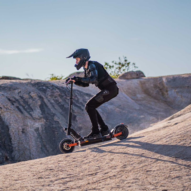 Load image into Gallery viewer, Joyor S5-Z electric scooter in action on a mountain slope, demonstrating its power and stability on rugged terrain with dual suspension