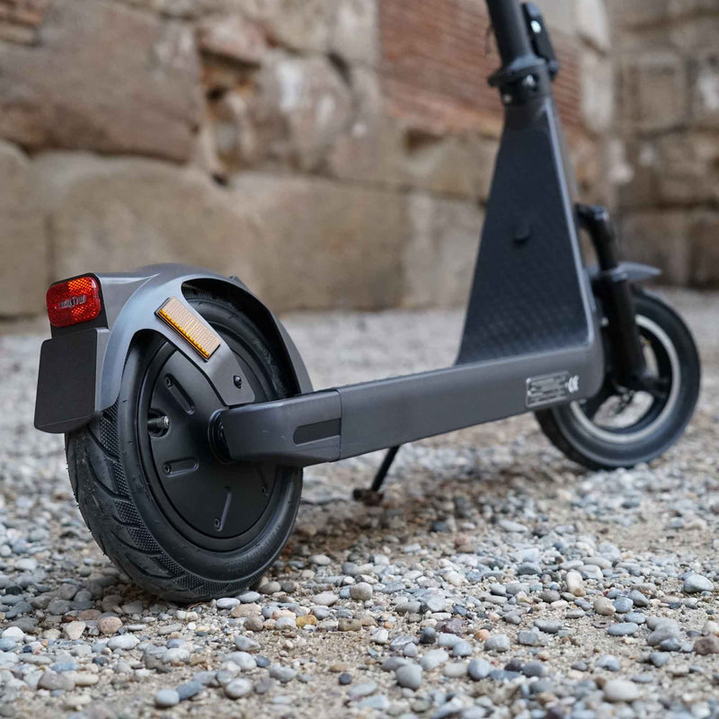 Cargue la imagen en el visor de la galería, Close-up of the rear wheel of the Joyor LiteGo electric scooter, parked in the city, showcasing its 10” tyre and motor