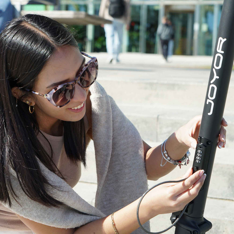 Cargue la imagen en el visor de la galería, Joyor LiteGo electric scooter with woman using lock, showcasing secure and convenient urban mobility