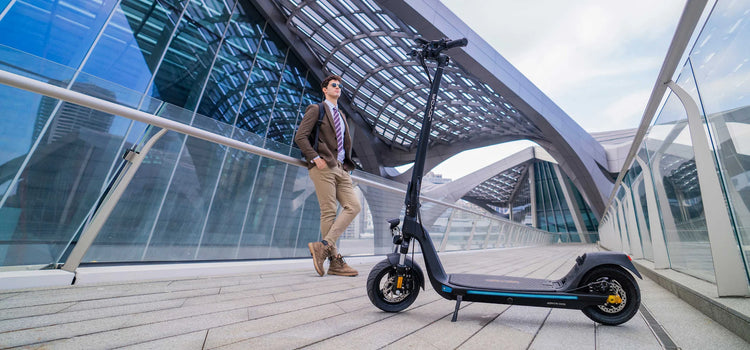 Joven junto a patinete eléctrico C10 DGT autonomía media-alta para desplazamientos diarios