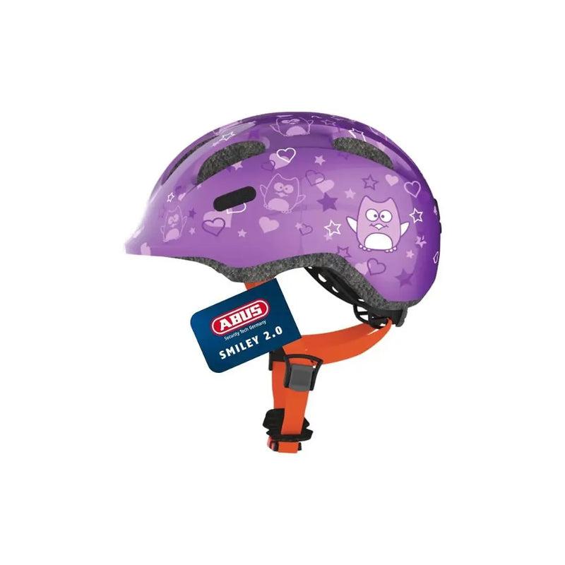 Charger l’image dans la visionneuse de la galerie, A purple kids' bicycle helmet with an owl and heart pattern, featuring an orange chin strap and a blue ABUS Smiley 2.0 hangtag.
